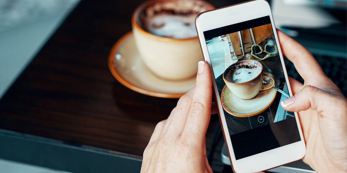 pessoa fotografando uma xícara de café com smartphone